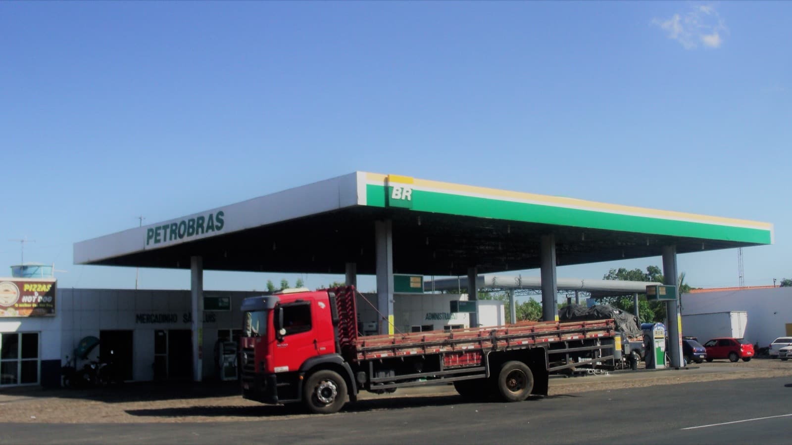 Foto de arquivo de um posto de combustíveis da bandeira Petrobras/BR visto de fora, com caminhão de carga vermelho estacionado em frente, em dia de céu azul