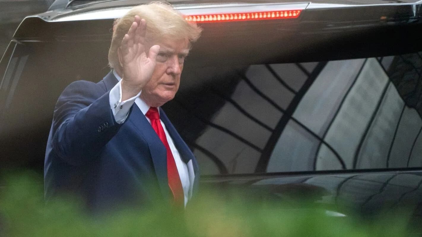 Donald Trump acenando ao entrar em veículo oficial