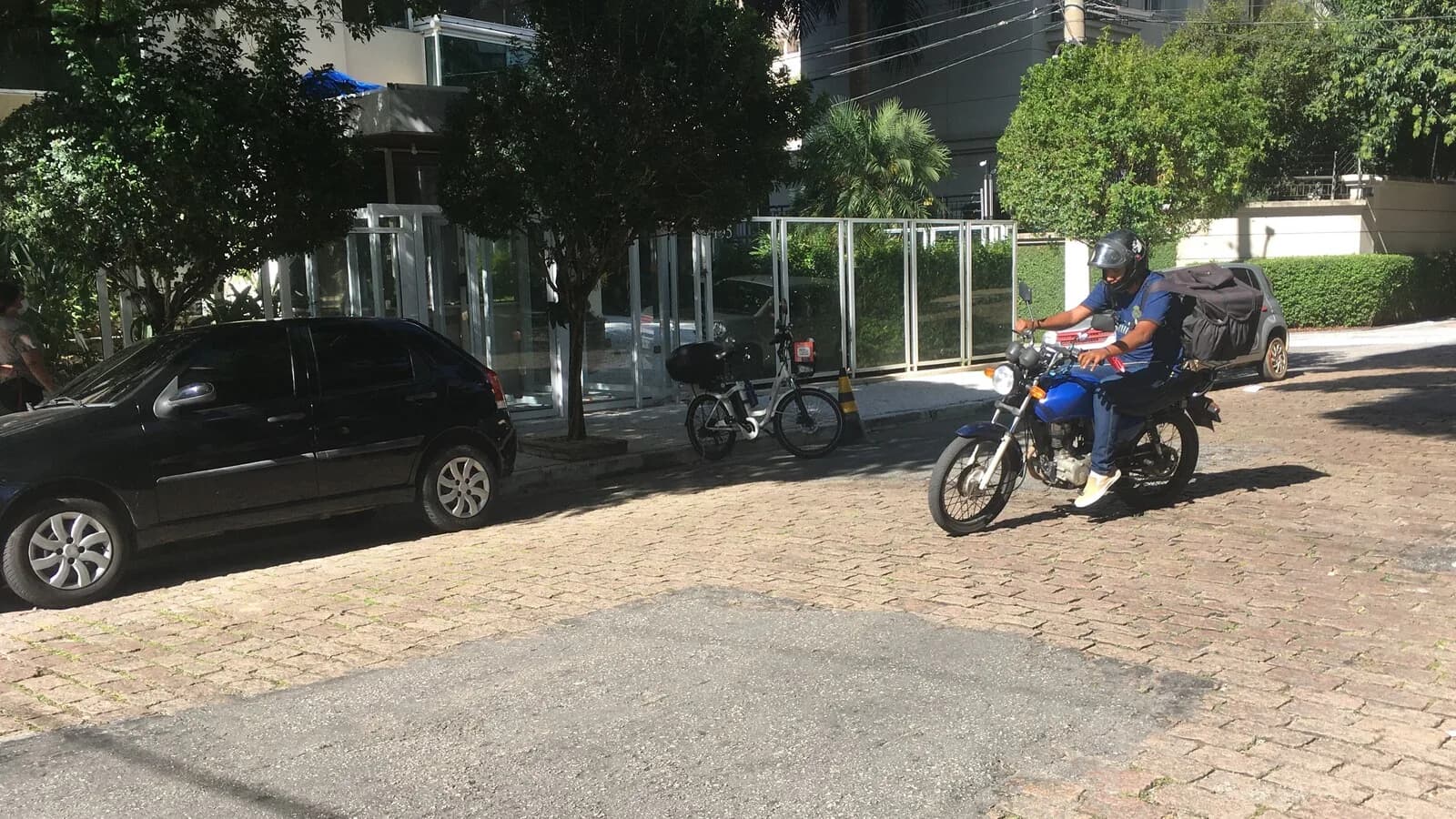 Entregador de aplicativo em motocicleta com baú de entrega na rua