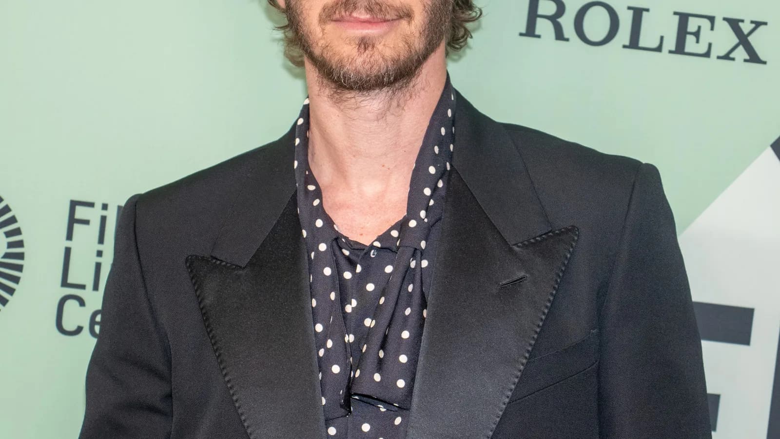 Andrew Garfield em evento de divulgação de filme, usando terno escuro