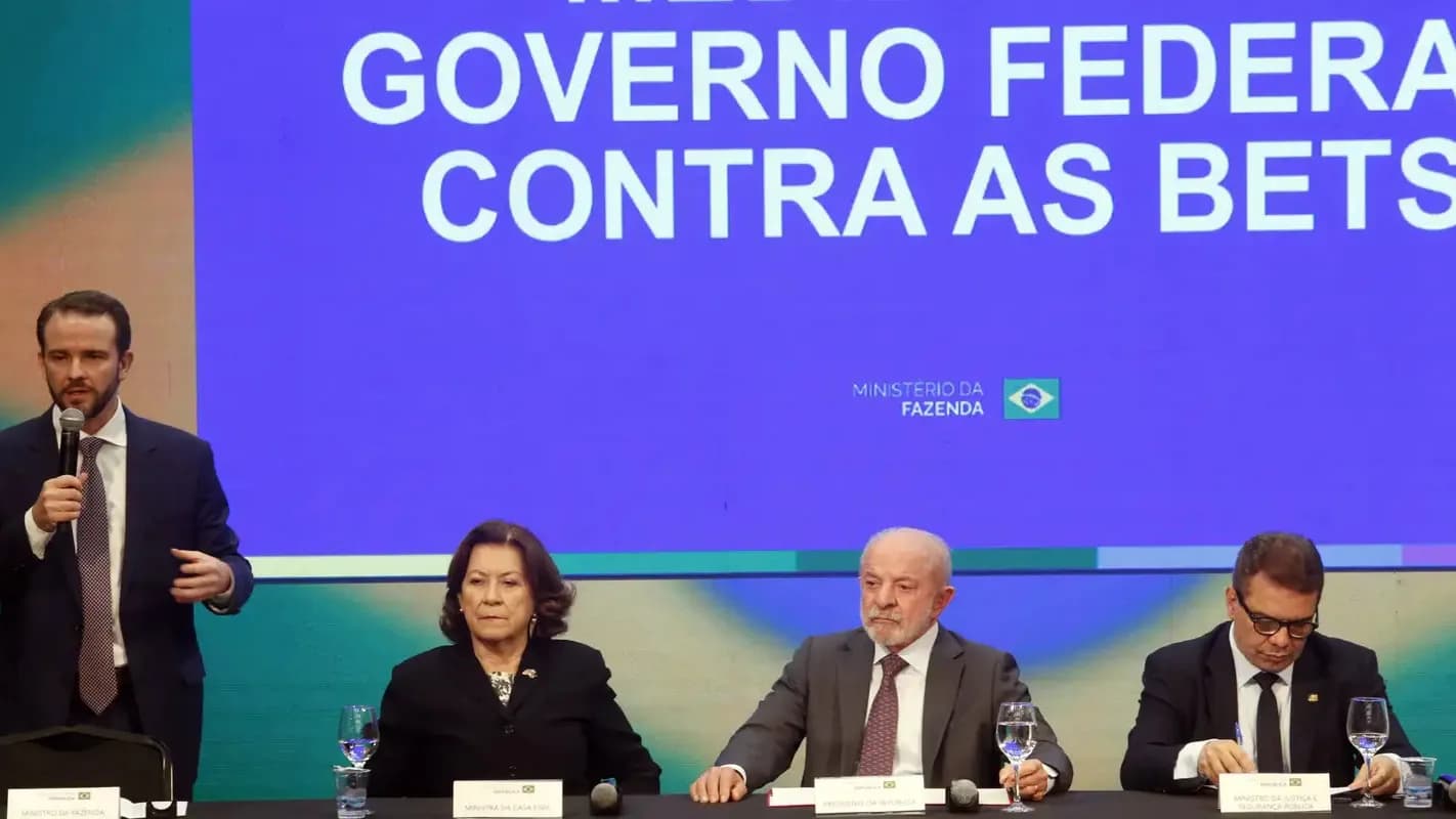 Dario Durigan discursa ao microfone ao lado de Lula em evento do governo federal (foto de arquivo)