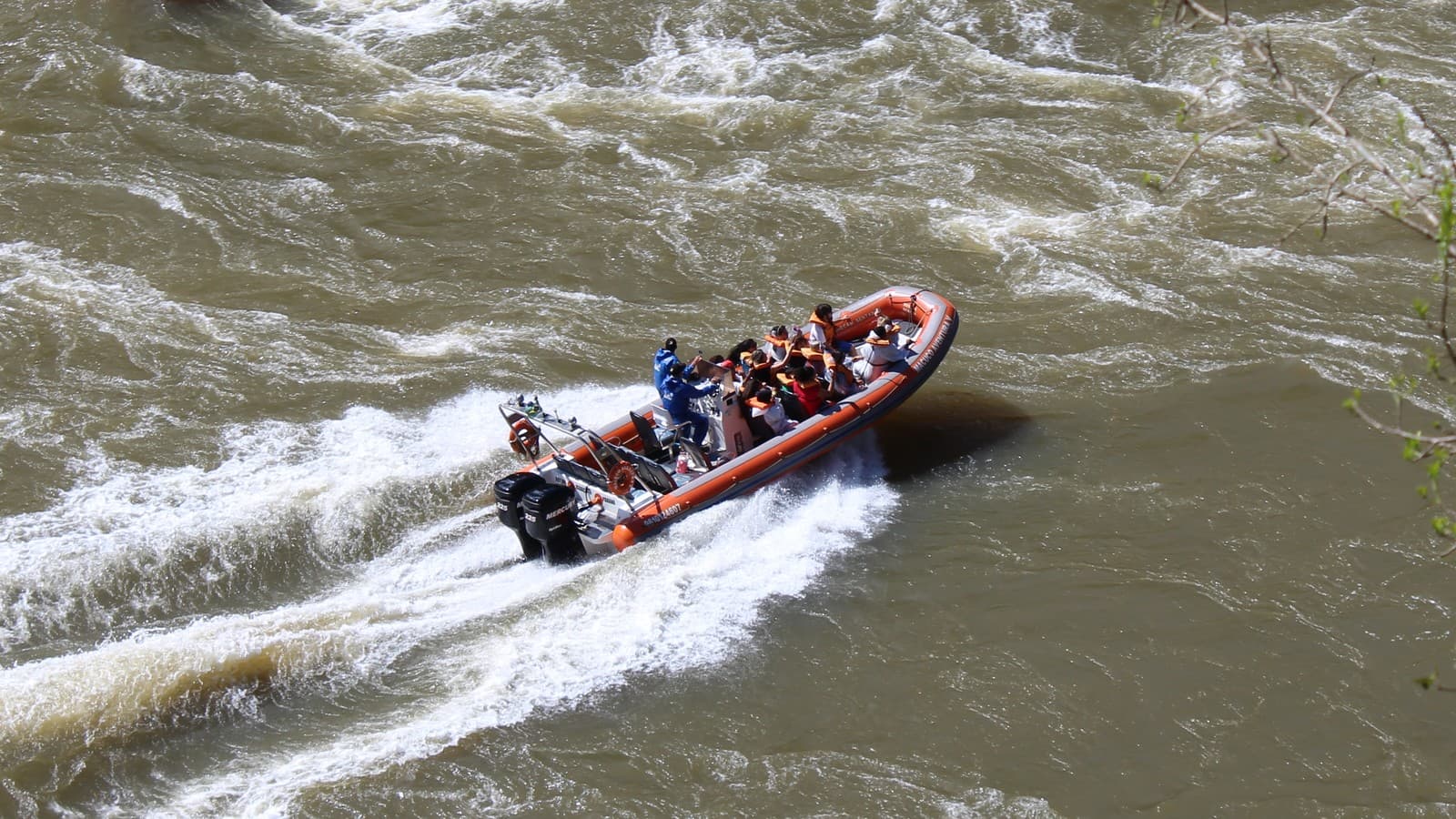 Bote inflável laranja com turistas de colete salva-vidas navega pelas corredeiras do rio Iguaçu, no Parque Nacional do Iguaçu, em imagem de arquivo de 2016