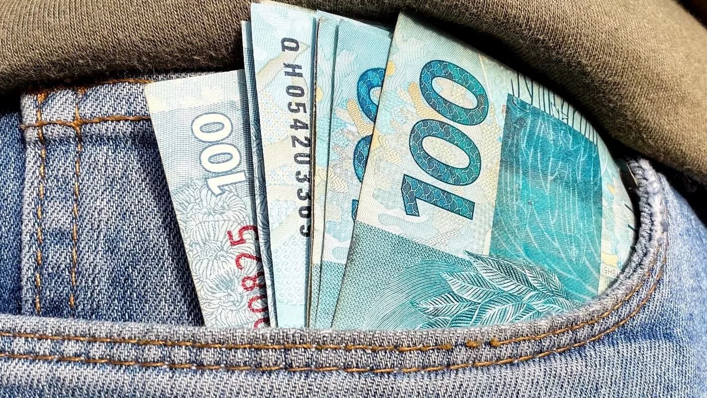 Notas de real de 100 reais no bolso de uma calça jeans