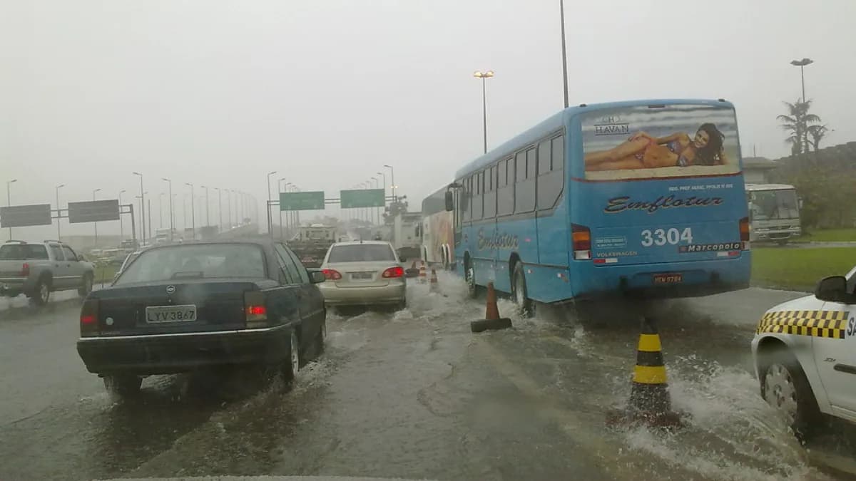 Carros e ônibus trafegam por rua alagada em São Paulo durante temporal