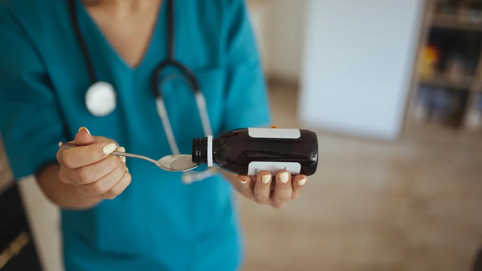 Enfermeira com jaleco e estetoscópio administra medicamento em ambiente hospitalar (foto de arquivo)