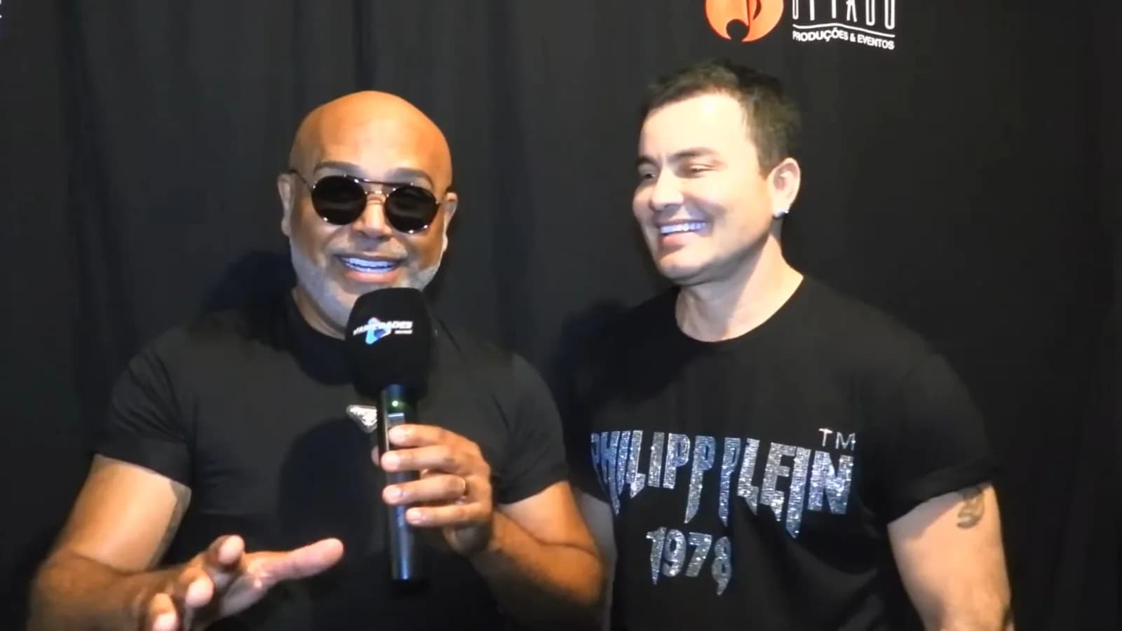 Rick e Renner sorrindo lado a lado durante entrevista ao programa Variedades