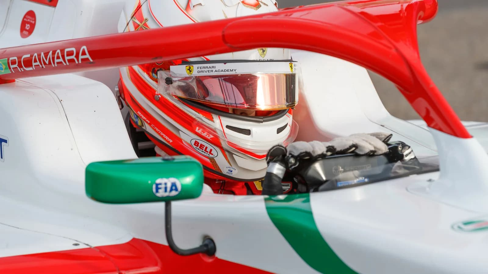 Piloto dentro do cockpit de carro de corrida com o nome R.Camara na lateral