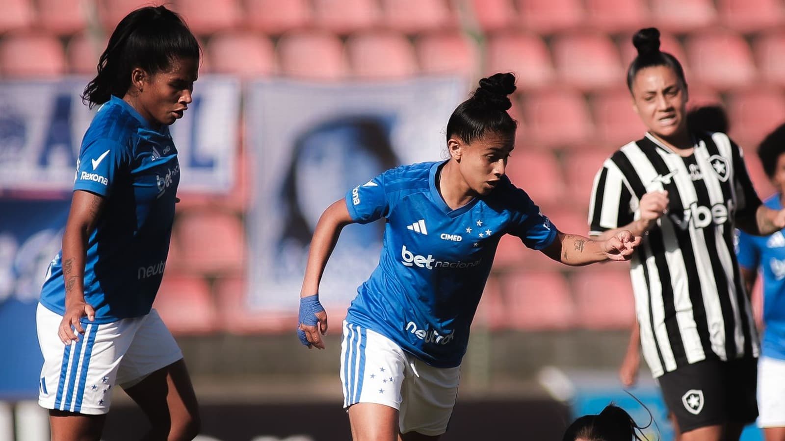 Jogadoras do Cruzeiro, de uniforme azul, e do Botafogo, de camisa listrada em preto e branco, durante a partida do Brasileirão Feminino na Arena do Jacaré