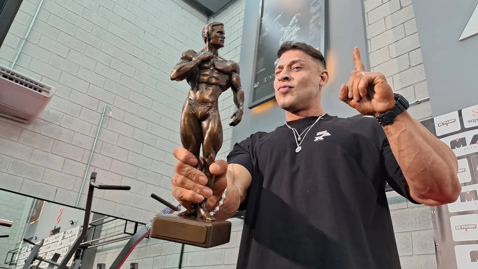 Ramon Dino segura troféu do Mr. Olympia em academia