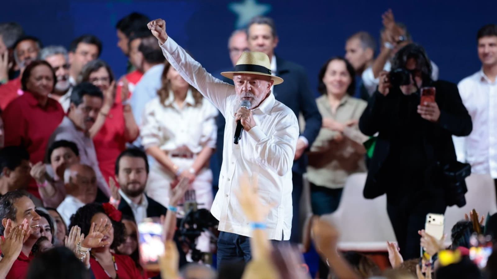 Lula discursa com o punho erguido cercado de apoiadores em evento de campanha à reeleição