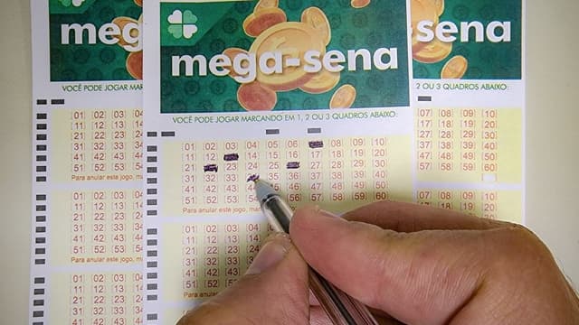 Mão de um apostador marca dezenas com caneta em volantes da Mega-Sena, em foto de arquivo