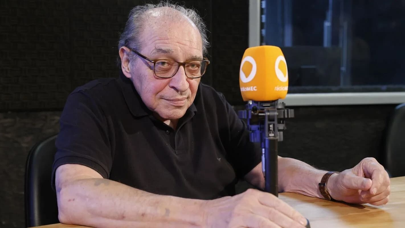 Ruy Castro em estúdio de rádio, sentado diante de um microfone