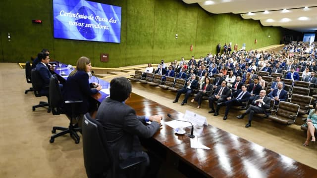 Auditório lotado durante cerimônia de posse de novos servidores públicos, com telão exibindo o texto 'Cerimônia de Posse dos novos servidores'