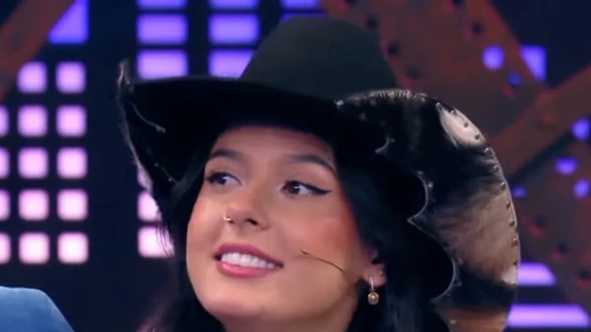Ana Castela sorri durante entrevista de televisão usando chapéu