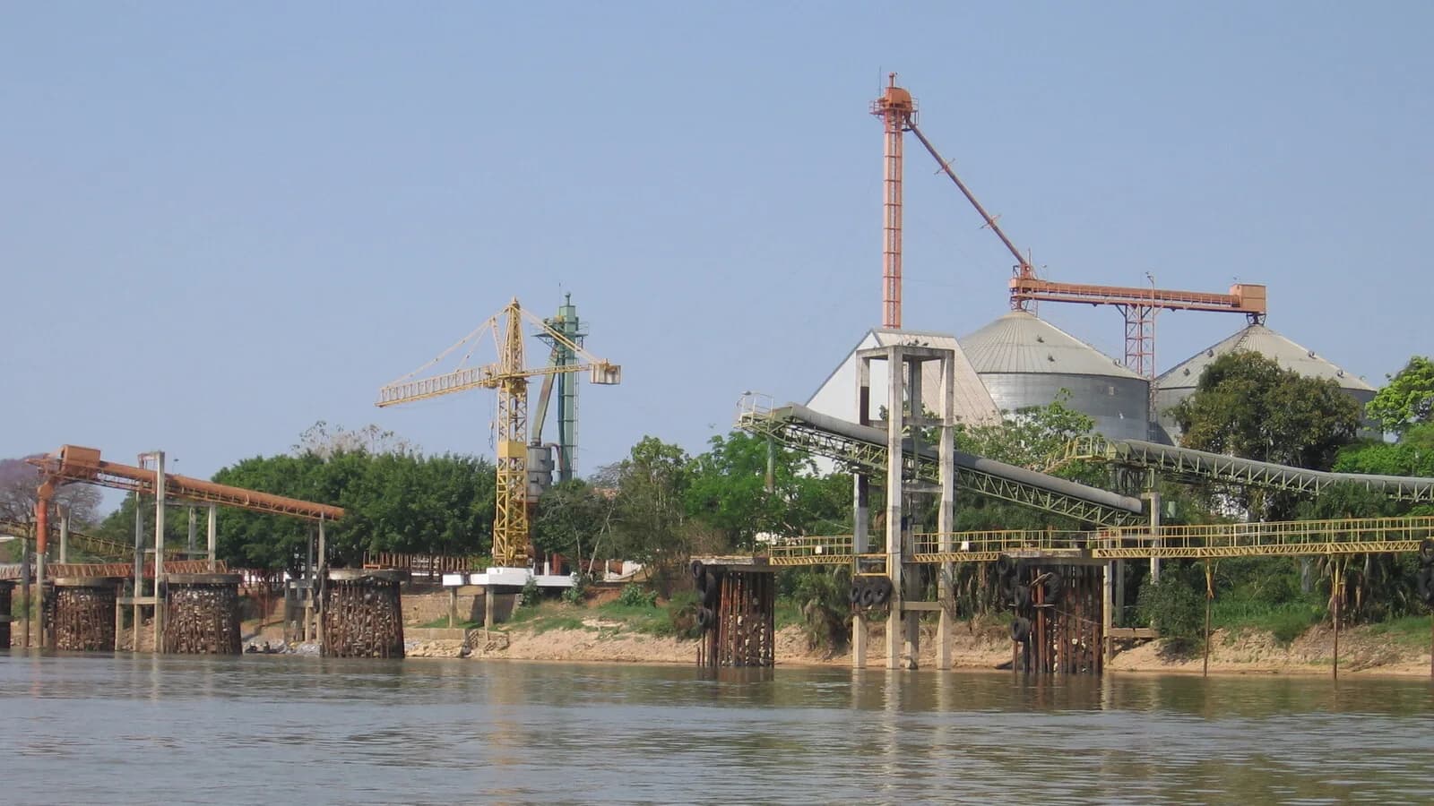 Estrutura de silos e guindastes para carregamento de grãos em terminal de exportação às margens de um rio