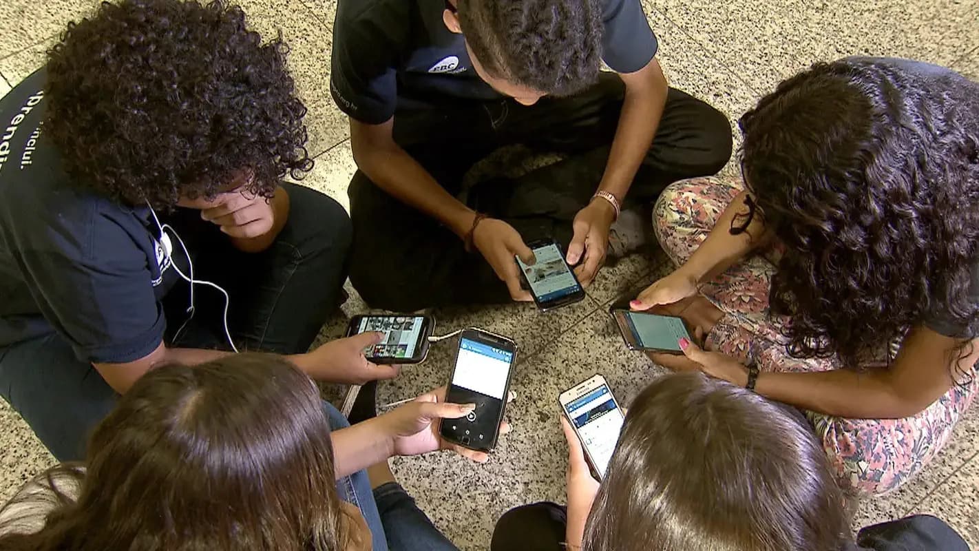 Jovens usam celulares em grupo