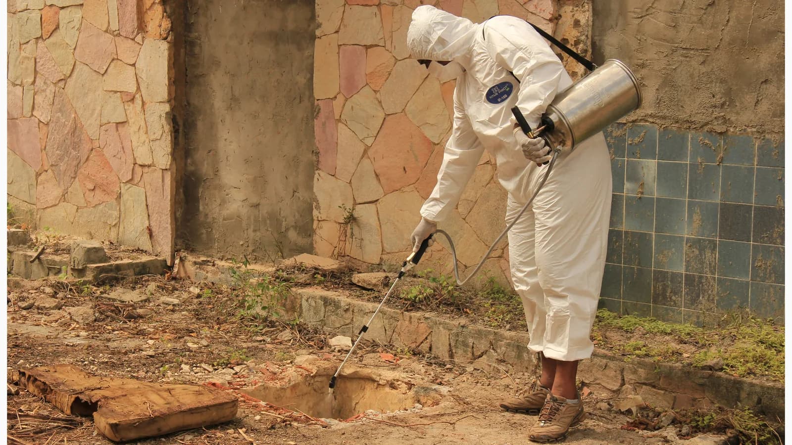 Agente de saúde em traje de proteção aplica inseticida contra o mosquito Aedes aegypti