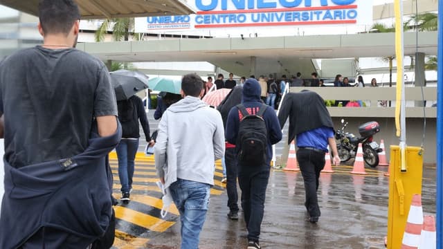 Foto de arquivo: estudantes caminham sob chuva em direção à entrada de um centro universitário privado em Brasília