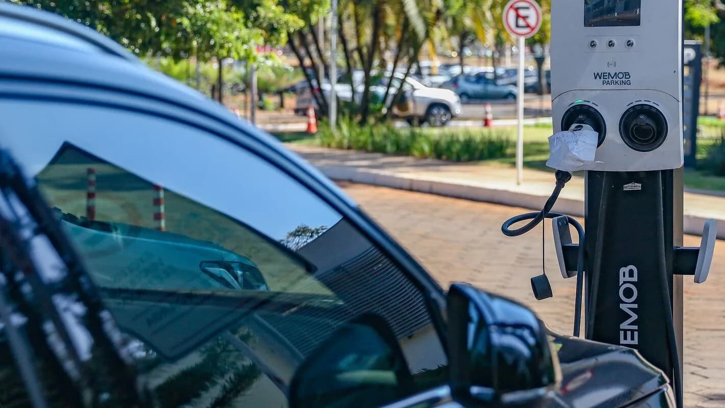 Carro elétrico conectado a um ponto de recarga pública em via urbana no Brasil