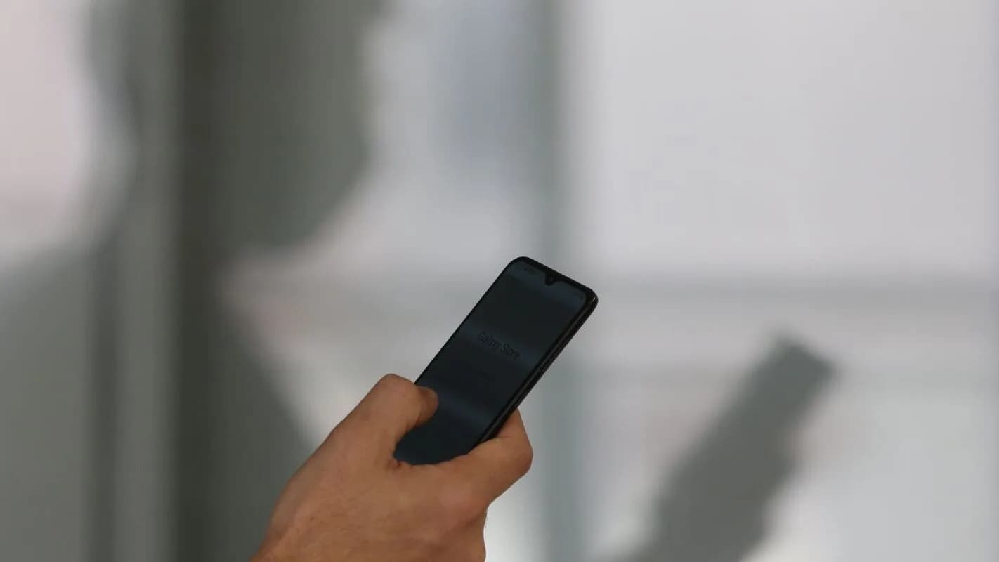 Mão segurando um celular ao acessar um aplicativo, em referência às apostas on-line