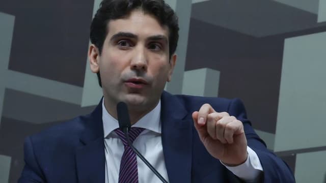 Presidente do Banco Central, Gabriel Galípolo, fala em microfone durante audiência em comissão, gesticulando com a mão