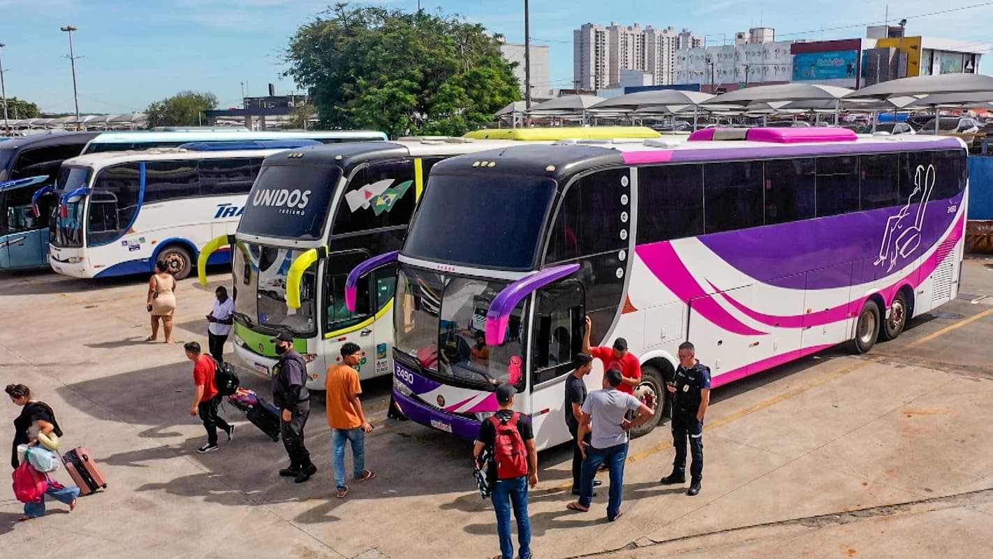 Fiscais e passageiros ao lado de ônibus apreendidos em operação da ANTT contra transporte clandestino