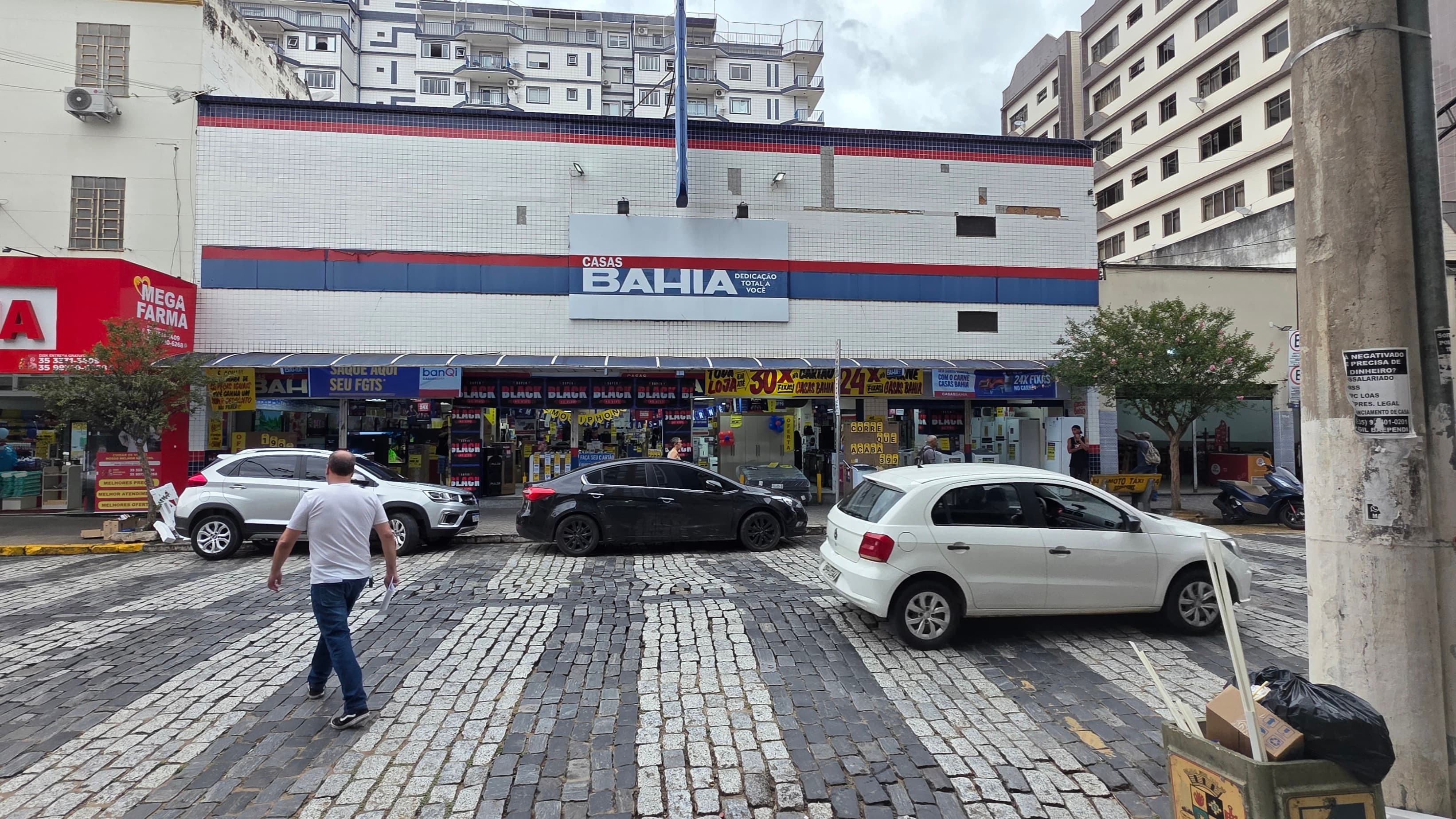 Fachada de uma loja da rede Casas Bahia em rua de comércio, com pedestres passando em frente