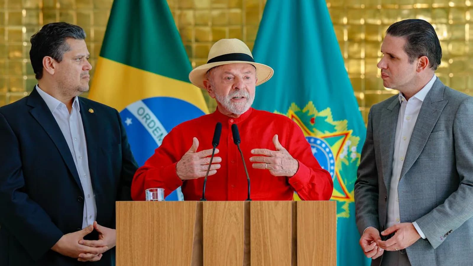 Lula discursa ao microfone entre Davi Alcolumbre e Hugo Motta, com bandeiras ao fundo