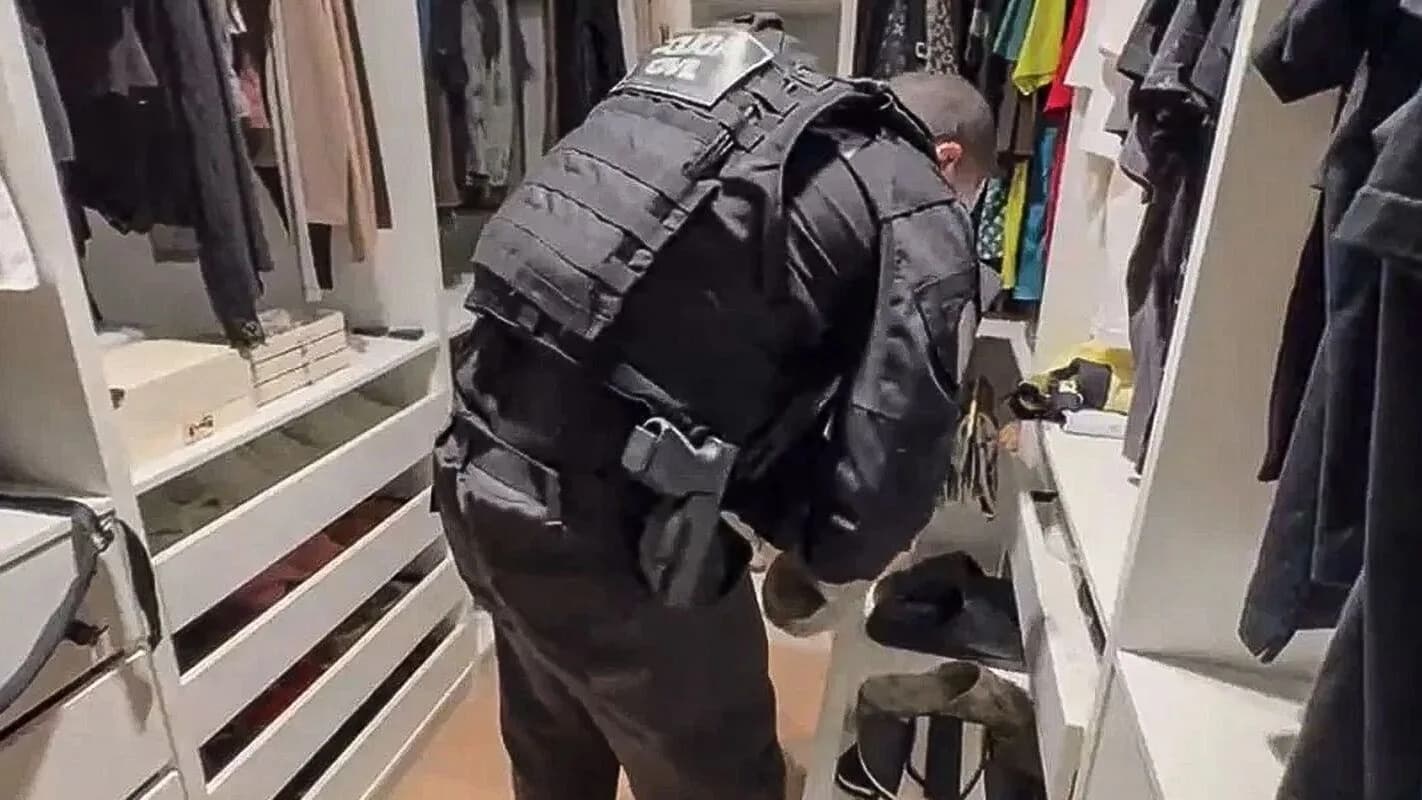 Agente de polícia revista guarda-roupa durante busca e apreensão em operação policial (foto de arquivo, ilustrativa)