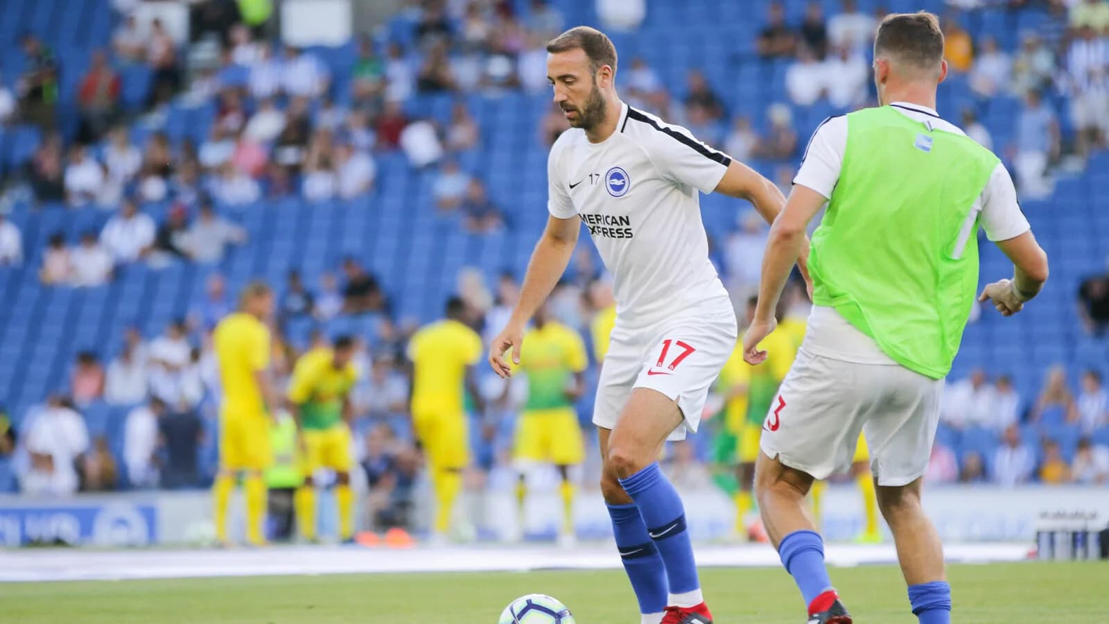 Jogador do Brighton conduz a bola durante partida, com torcida ao fundo, foto de arquivo