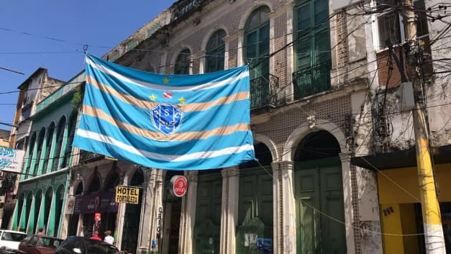 Bandeira do Paysandu, bicolor azul e branca, pendurada na fachada de um prédio histórico