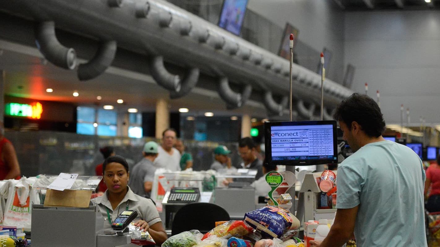 Consumidor faz compras no caixa de um supermercado lotado (foto de arquivo)