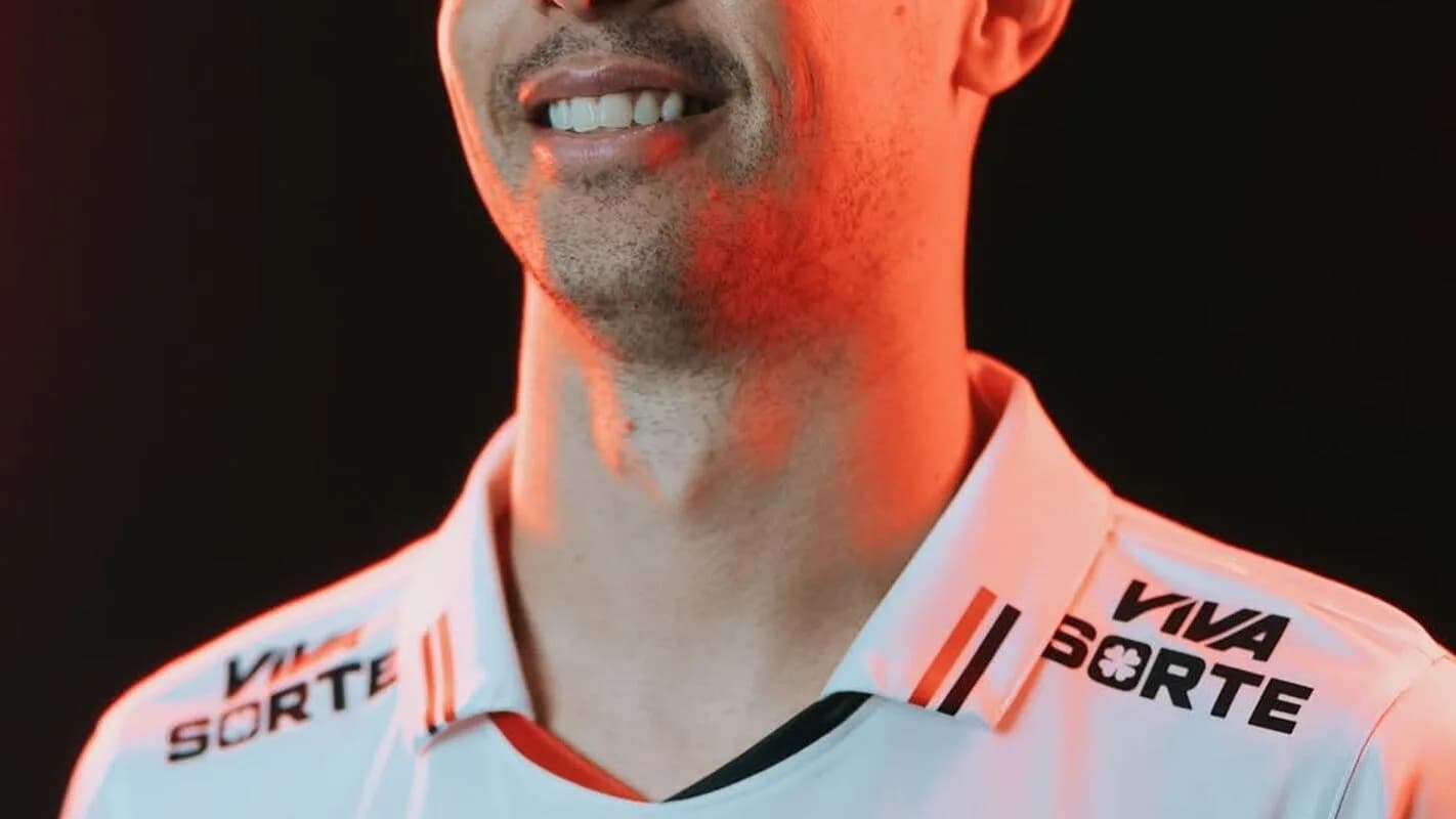 Jogador do São Paulo sorri em close, usando o uniforme do clube