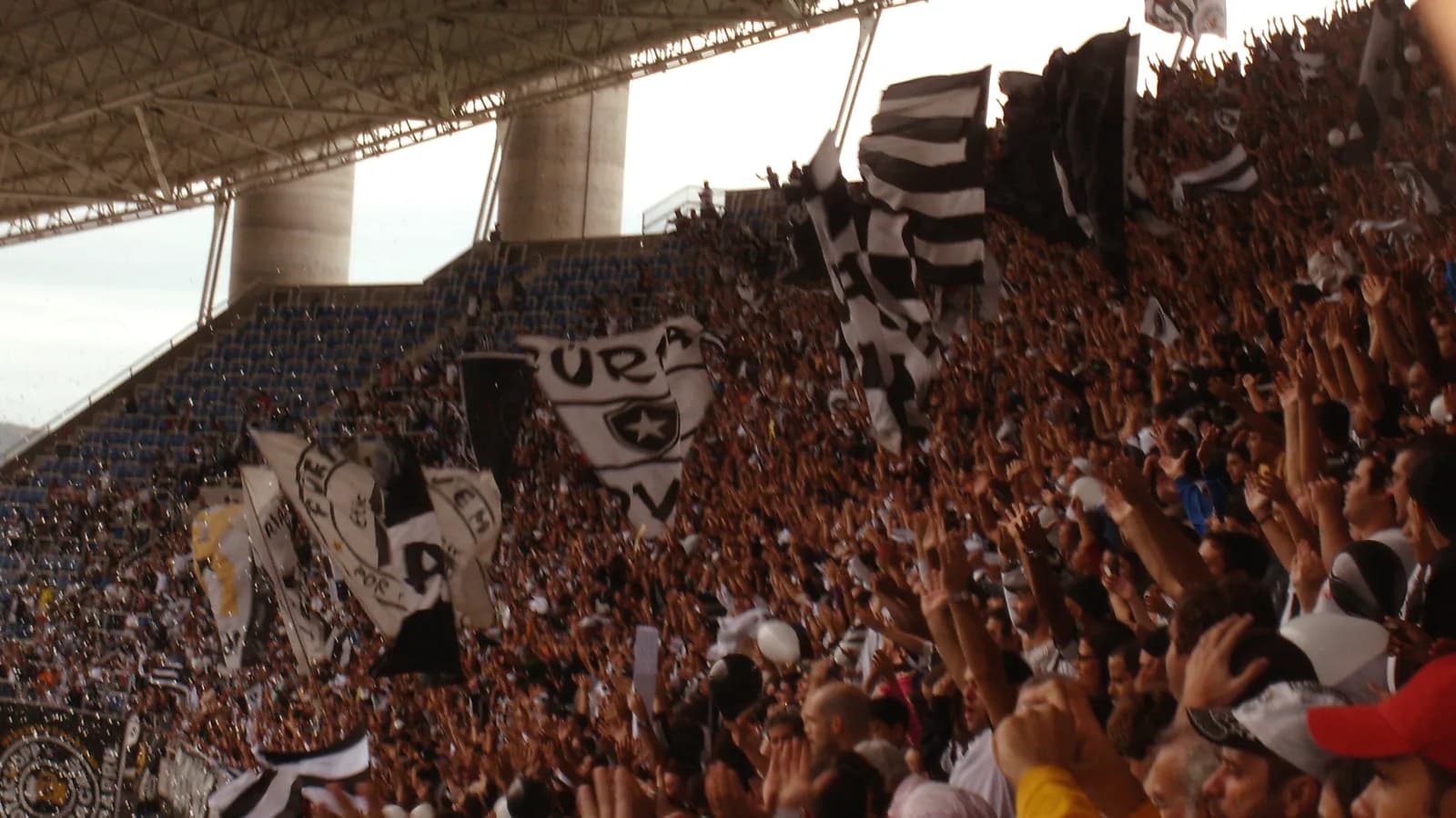 Torcida do Botafogo com bandeiras e cores do clube no estádio