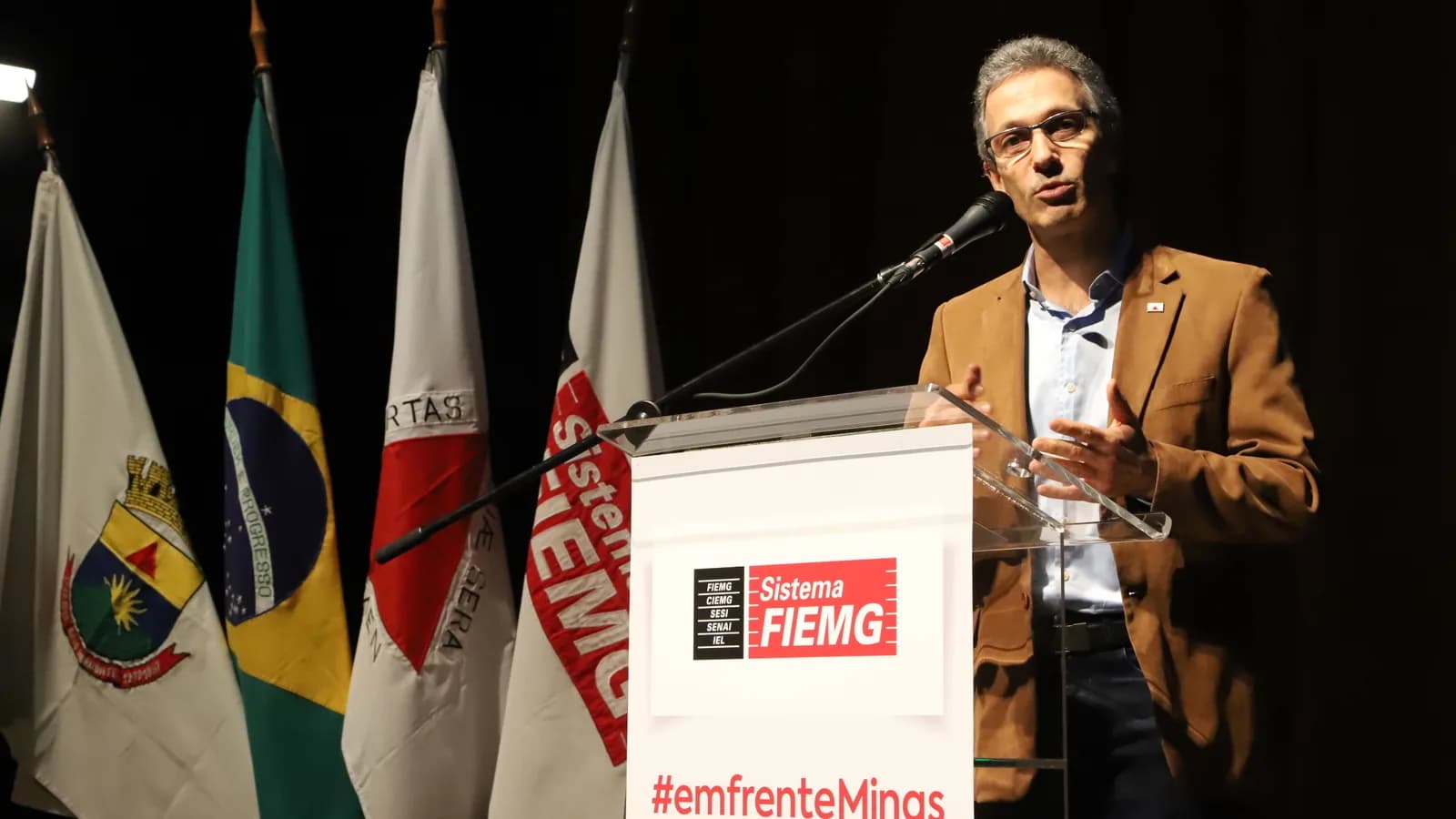 Romeu Zema discursa em púlpito diante de bandeiras, durante evento da Fiemg