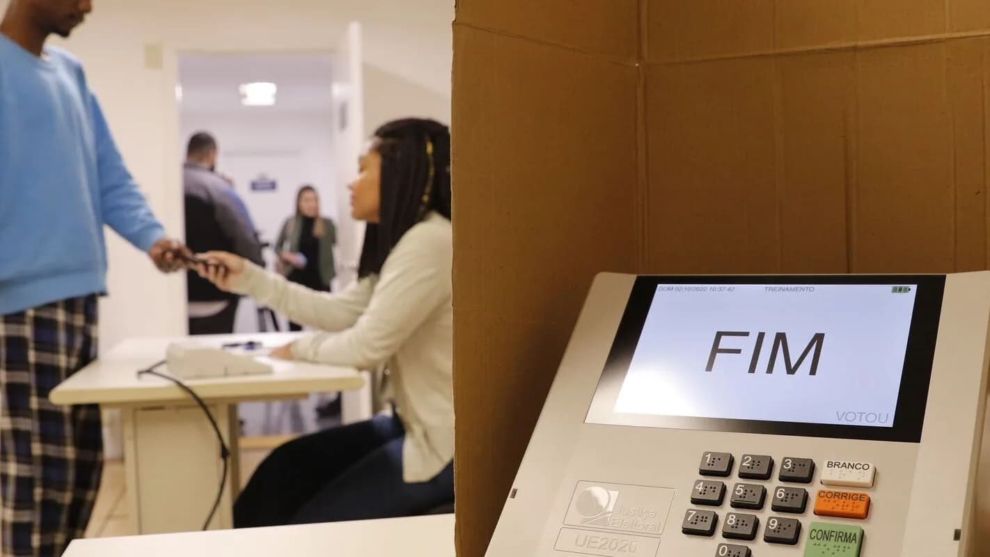 Eleitor vota em urna eletrônica com a palavra FIM na tela, em seção eleitoral no exterior
