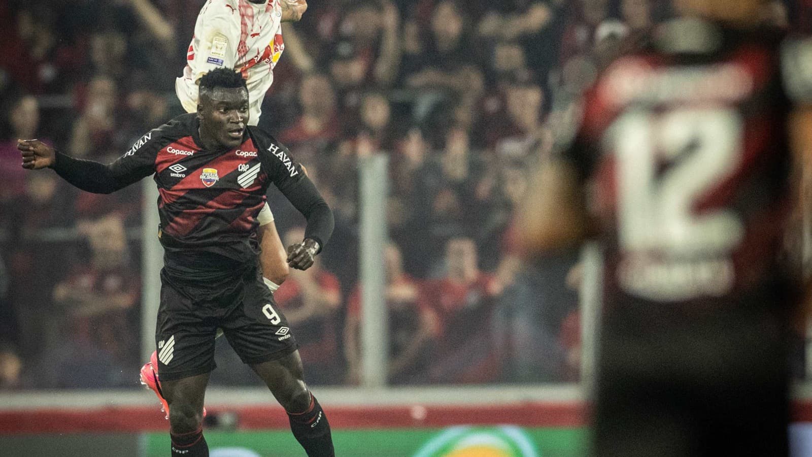 Jogador do Red Bull Bragantino cabeceia a bola durante disputa com defensor do Athletico-PR na Arena da Baixada