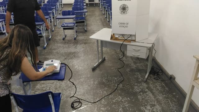 Mesária libera urna eletrônica em cabina de votação; foto de arquivo do processo eleitoral