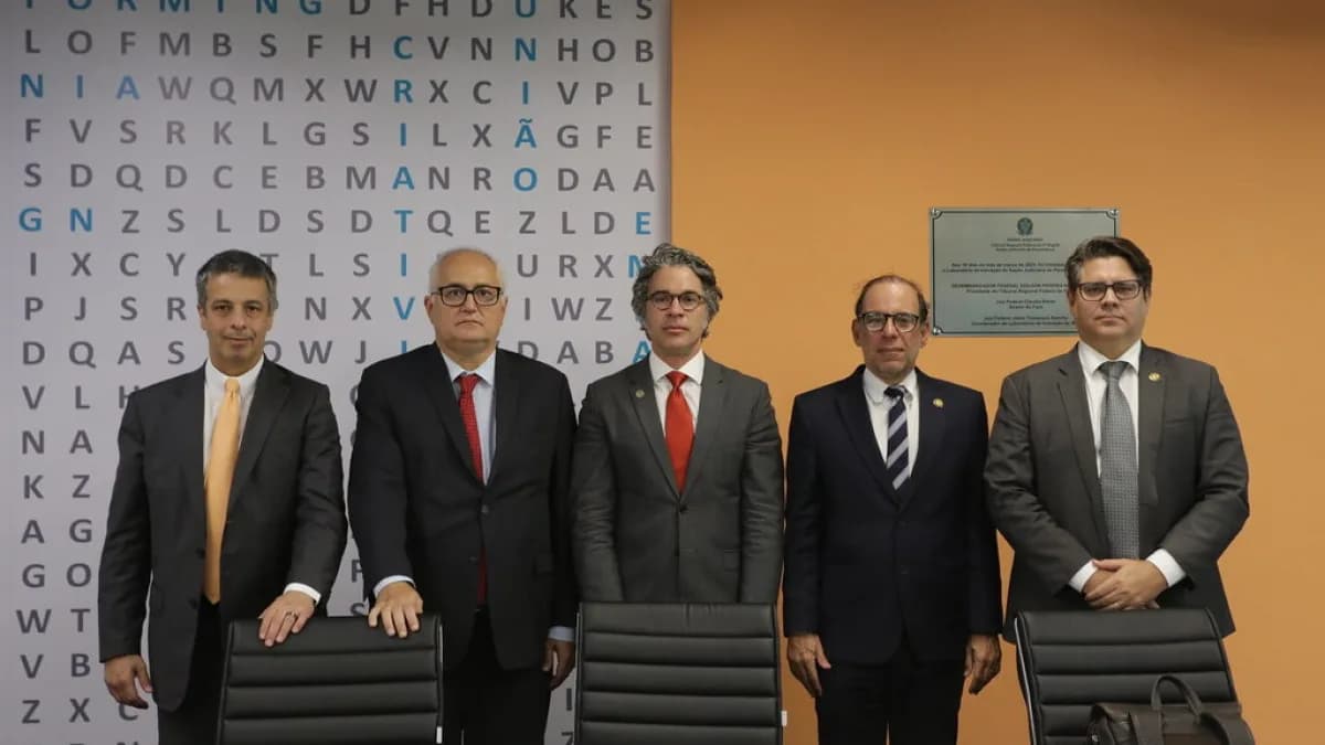 Grupo de autoridades da Justiça Federal reunido em frente a uma placa institucional
