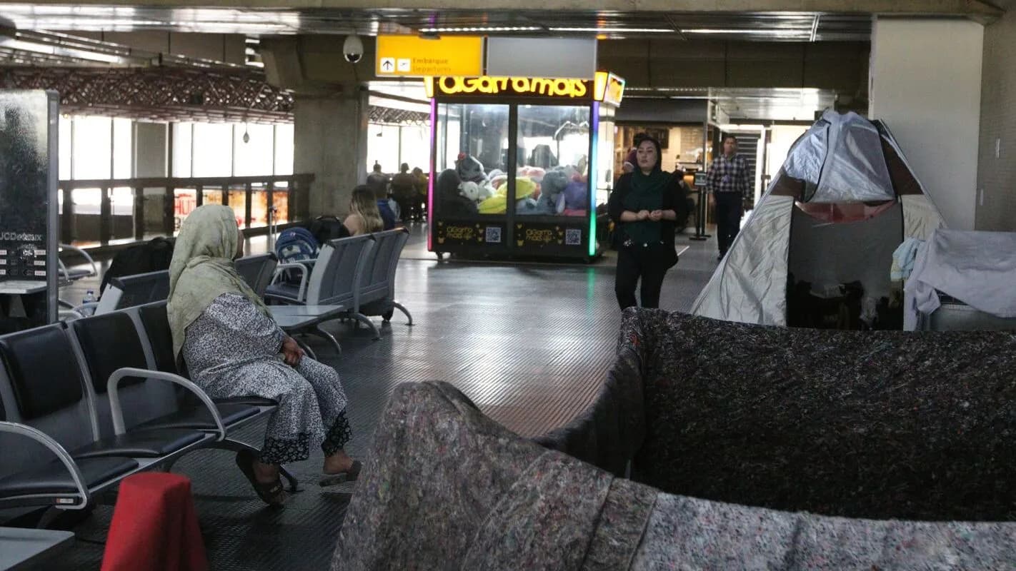 Imigrantes em área de espera de aeroporto brasileiro, com malas e colchões, foto de arquivo