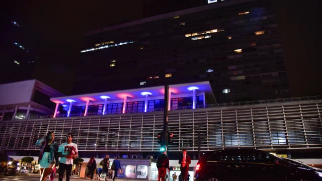 Fachada do consulado dos Estados Unidos em São Paulo durante evento, com pessoas na calçada à noite
