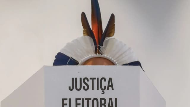 Cocar indígena sobre um púlpito com a inscrição 'Justiça Eleitoral'