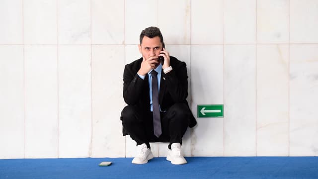 Senador Cleitinho Azevedo agachado ao telefone em corredor do Senado