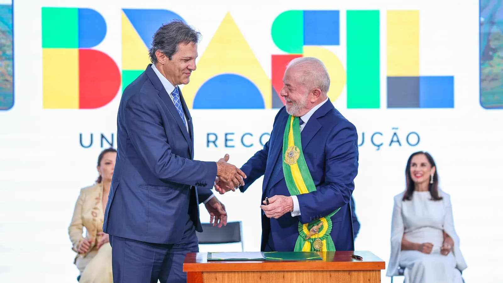 Fernando Haddad cumprimenta o presidente Lula em cerimônia oficial, ambos sorridentes