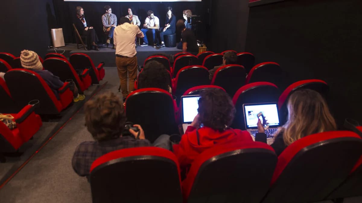 Jovens profissionais usam notebooks e celulares lado a lado durante evento