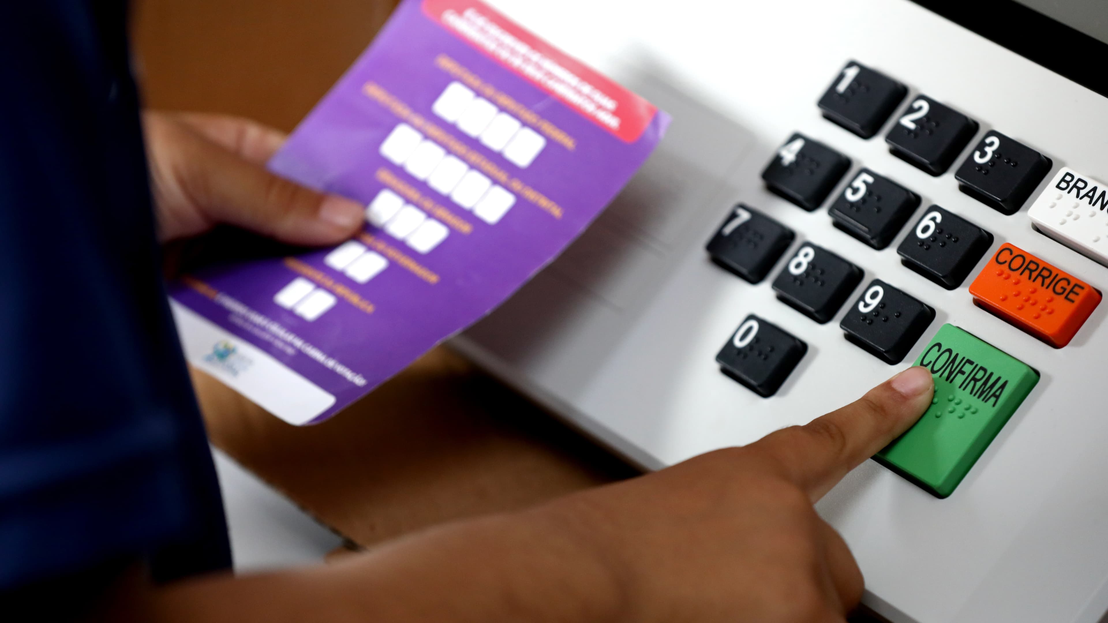 Close de mãos confirmando o voto na urna eletrônica, com botões em braile (foto ilustrativa)
