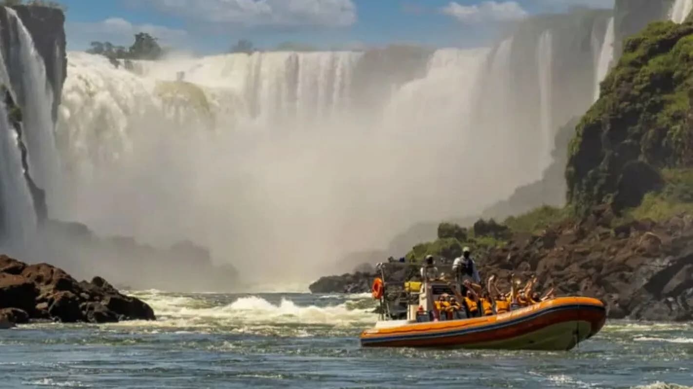 Cataratas do Iguaçu com grande volume de água e barco de turistas no rio