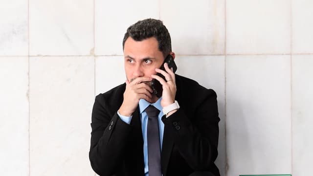 O senador Cleitinho Azevedo, de terno preto, camisa azul-clara e gravata, agachado ao telefone junto a uma parede de mármore em um corredor do Senado Federal, com a mão junto à boca. Foto de arquivo feita em abril de 2025