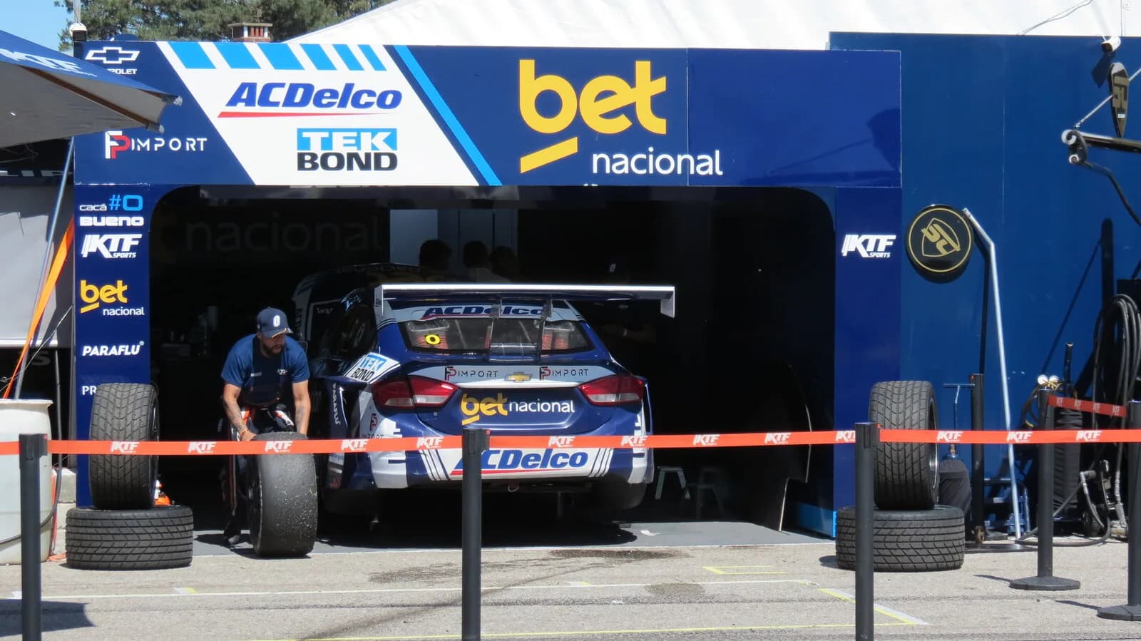 Mecânico empurra pneu ao lado de carro da Stock Car Pro Series no box (foto de arquivo)