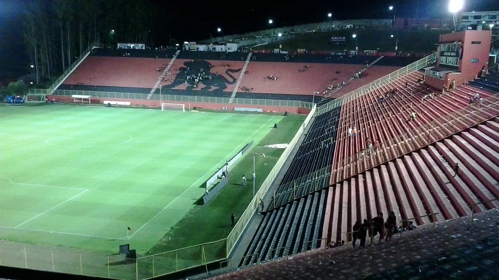 Vista interna do estádio Barradão à noite, com o emblema do leão do Vitória nas arquibancadas